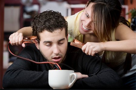 simsearch:400-04748544,k - Young woman holding jumper cables coming out of coffee mug to man's head Stock Photo - Budget Royalty-Free & Subscription, Code: 400-04554628