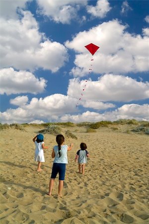 pictures of boy fly kites in the sky - three kids on a beach playing with a red kite Stock Photo - Budget Royalty-Free & Subscription, Code: 400-04556337