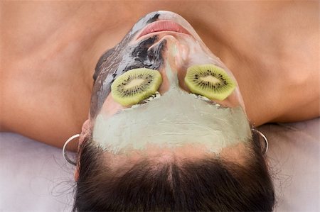 simsearch:400-05356153,k - Woman lying down on her back in spa, with special facial mask applied on her face. The mask consist of three colors, each cover different part and eyes are covered by slice of kiwi Stock Photo - Budget Royalty-Free & Subscription, Code: 400-04550094