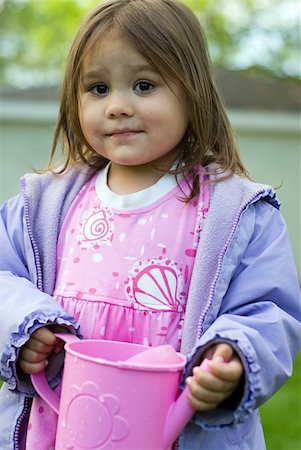 A young girl standing outside holding a pink watering can Stock Photo - Budget Royalty-Free & Subscription, Code: 400-04567885