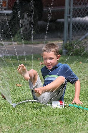 Young boy playing in the sprinkler with his feet in the air. Stock Photo - Budget Royalty-Free & Subscription, Code: 400-04569295