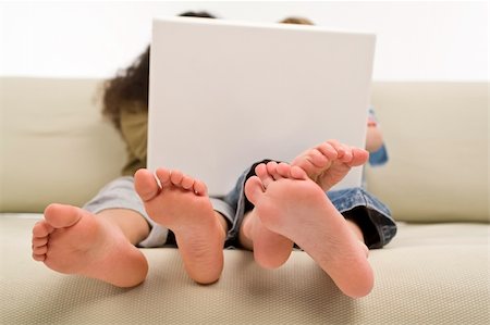 Two young children surfing the wold wide web on a laptop while sitting on a settee Stock Photo - Budget Royalty-Free & Subscription, Code: 400-04575374
