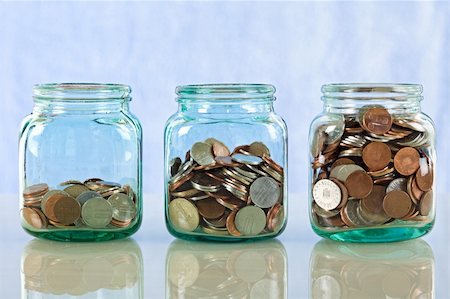 Saving money concept - coins in old jars on reflective surface against blue background Stock Photo - Budget Royalty-Free & Subscription, Code: 400-04594020