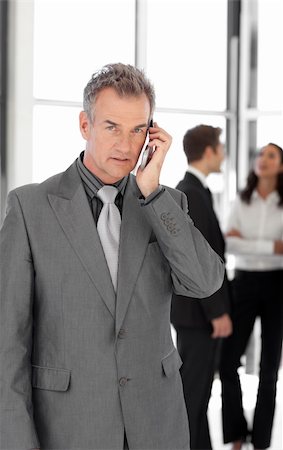 simsearch:400-05145011,k - Senior Businessman talking on cellphonein front of Businesspeople Stock Photo - Budget Royalty-Free & Subscription, Code: 400-04598736