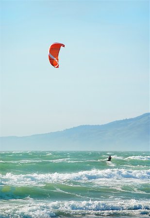 simsearch:400-03992760,k - Surfer with red kite surfing off the beach in San Francisco, California on a sunny day. Stock Photo - Budget Royalty-Free & Subscription, Code: 400-04599473