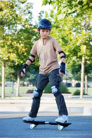 simsearch:400-05737917,k - Teenage boy riding a skateboard in a parking lot with trees in the background on a sunny day. Stock Photo - Budget Royalty-Free & Subscription, Code: 400-04592102