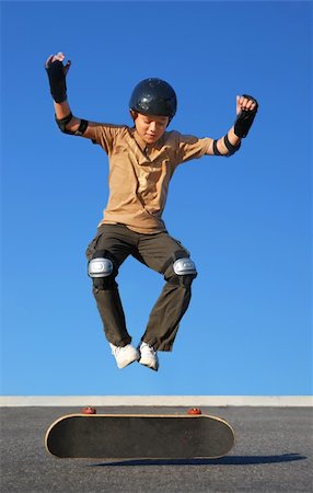 simsearch:400-05737917,k - Boy with protective gear jumping high from a skateboard with blue background. Stock Photo - Budget Royalty-Free & Subscription, Code: 400-04608308