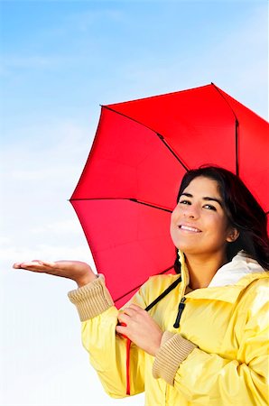 Portrait of beautiful smiling girl wearing yellow raincoat holding red umbrella checking for rain Stock Photo - Budget Royalty-Free & Subscription, Code: 400-04619872