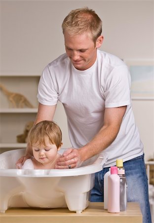 A young father is giving his baby daughter a bath in a childs tub.  He is smiling and looking down at his daughter.  Vertically framed shot. Foto de stock - Super Valor sin royalties y Suscripción, Código: 400-04622686