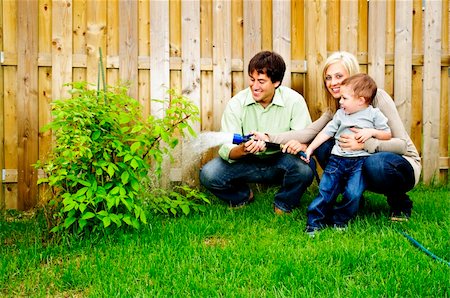 family backyard gardening not barbeque - Happy family in backyard watering plant with hose Stock Photo - Budget Royalty-Free & Subscription, Code: 400-04636777