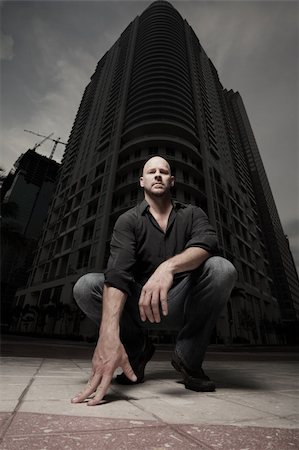 Man squatting with a tower in the background Stock Photo - Budget Royalty-Free & Subscription, Code: 400-04646809