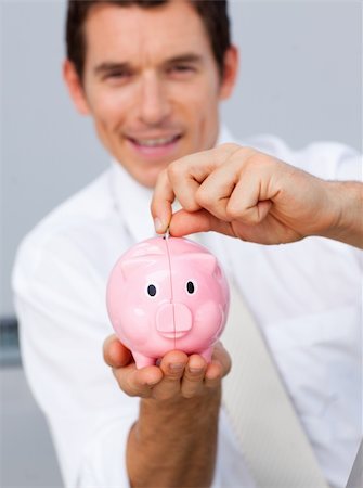 simsearch:400-05715207,k - Attractive businessman saving money in a piggybank in the office Stock Photo - Budget Royalty-Free & Subscription, Code: 400-04659665