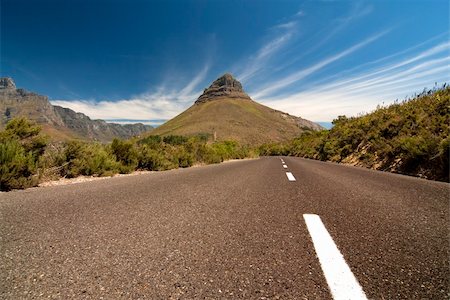 simsearch:400-05112302,k - Road leading toward a mountain in the background with blue sky and clouds Stock Photo - Budget Royalty-Free & Subscription, Code: 400-04651145