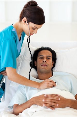 simsearch:400-05748252,k - Confident doctor checking the pulse of a patient lying on a hospital bed Stock Photo - Budget Royalty-Free & Subscription, Code: 400-04660721