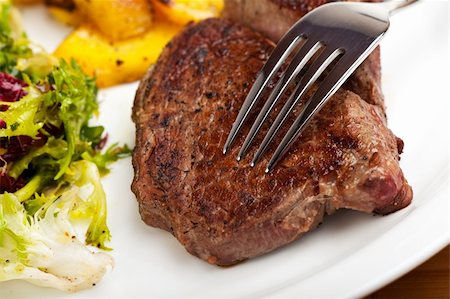 fine dining restaurant - closeup of a silver fork on a steak Photographie de stock - Aubaine LD & Abonnement, Code: 400-04677283