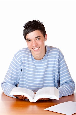 simsearch:400-04505681,k - Young student is sitting on desk with his books and smiles happy into camera. Isolated on white. Stock Photo - Budget Royalty-Free & Subscription, Code: 400-04684325