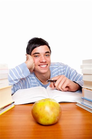 simsearch:400-04505681,k - Young handsome student smiles happy and sits between study books at desk. Isolated on white. Stock Photo - Budget Royalty-Free & Subscription, Code: 400-04684326