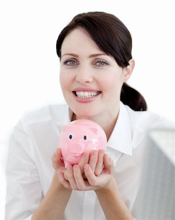 simsearch:400-05715208,k - Businesswoman holding a piggybank against a white background smiling at the camera Stock Photo - Budget Royalty-Free & Subscription, Code: 400-04687367