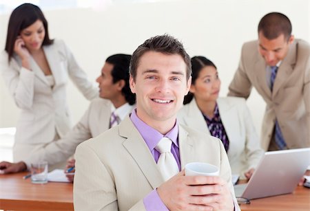 Cheerful manager drinking a coffee with his team in the background Stock Photo - Budget Royalty-Free & Subscription, Code: 400-04688108