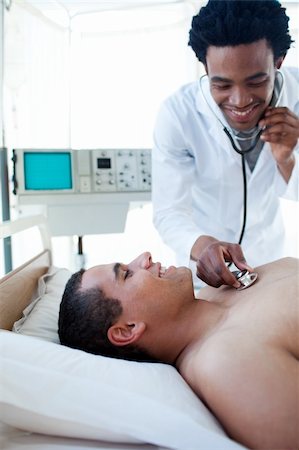 simsearch:400-05748252,k - Smiling doctor checking the pulse on a male patient lying on a hospital bed Stock Photo - Budget Royalty-Free & Subscription, Code: 400-04699460