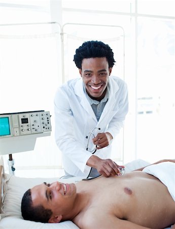 simsearch:400-05748252,k - Afro-american doctor examining a patient lying on a hospital bed Stock Photo - Budget Royalty-Free & Subscription, Code: 400-04699461
