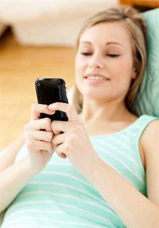simsearch:400-04212823,k - Bright young woman sending a text lying on a sofa at home Stock Photo - Budget Royalty-Free & Subscription, Code: 400-04700459