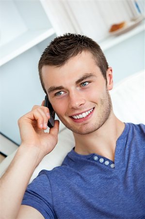 simsearch:400-04212823,k - Attractive man sitting on sofa and talking on phone in living room Stock Photo - Budget Royalty-Free & Subscription, Code: 400-04702346