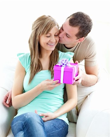 simsearch:400-04739802,k - Attractive boyfriend giving a present and a kiss to his glowing girlfriend against white background Stock Photo - Budget Royalty-Free & Subscription, Code: 400-04703872