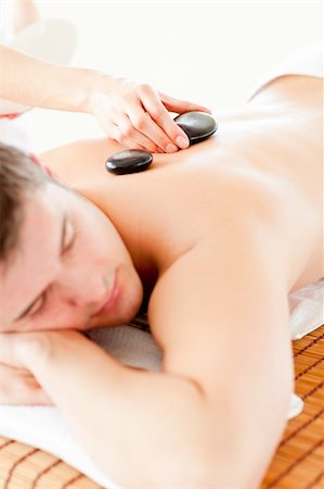 simsearch:400-04192063,k - Relaxed young man receiving a back massage with hot stone in a spa center Stock Photo - Budget Royalty-Free & Subscription, Code: 400-04715366