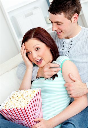 strangled men photos - Young couple lying on the sofa with popcorn and remote at home Stock Photo - Budget Royalty-Free & Subscription, Code: 400-04720005