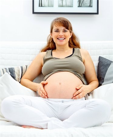 simsearch:400-04875116,k - Smiling beautiful pregnant woman sitting on sofa at home and touching her belly. Stock Photo - Budget Royalty-Free & Subscription, Code: 400-04747895