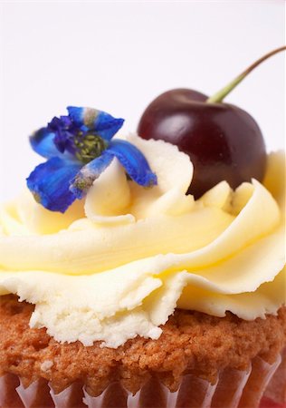 simsearch:400-04764403,k - Miniature vanilla cupcake with icing, fresh cherry and blue flower on white background. Macro shot, shallow depth of field Stock Photo - Budget Royalty-Free & Subscription, Code: 400-04754470