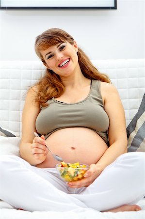 simsearch:400-04817039,k - Smiling beautiful pregnant woman relaxing on sofa at home with fruit salad  in hand Stock Photo - Budget Royalty-Free & Subscription, Code: 400-04754999