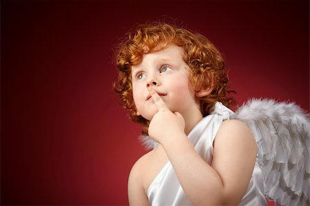 Portrait of the small thoughtful boy with wings behind the back on a red background Stock Photo - Budget Royalty-Free & Subscription, Code: 400-04756927