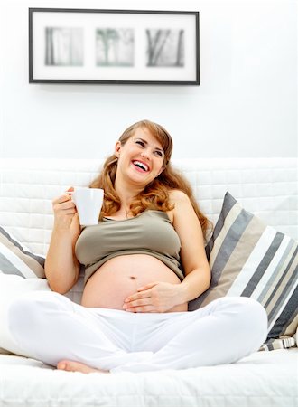 simsearch:400-04875116,k - Laughing beautiful pregnant woman relaxing on couch at home and  holding cup of tea in hand Stock Photo - Budget Royalty-Free & Subscription, Code: 400-04766943