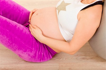 simsearch:400-05716366,k - Pregnant female sitting on floor at home and relaxing after exercising. Closeup. Stock Photo - Budget Royalty-Free & Subscription, Code: 400-04777261