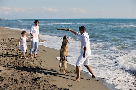 simsearch:400-05309800,k - happy young family in white clothing have fun and play with beautiful dog at vacations on beautiful beach Stock Photo - Budget Royalty-Free & Subscription, Code: 400-04779173