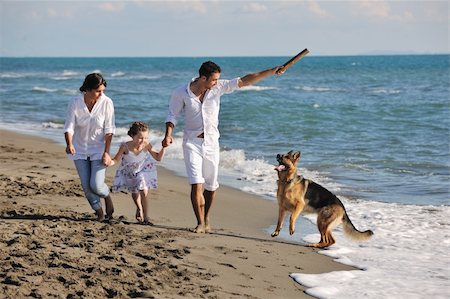 simsearch:400-05309800,k - happy young family in white clothing have fun and play with beautiful dog at vacations on beautiful beach Stock Photo - Budget Royalty-Free & Subscription, Code: 400-04779185