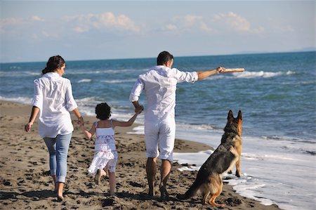 simsearch:400-05309800,k - happy young family in white clothing have fun and play with beautiful dog at vacations on beautiful beach Stock Photo - Budget Royalty-Free & Subscription, Code: 400-04779186