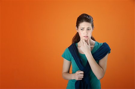 simsearch:400-05388090,k - Very worried young woman on orange background with fingers on chin while looking down Stock Photo - Budget Royalty-Free & Subscription, Code: 400-04831238