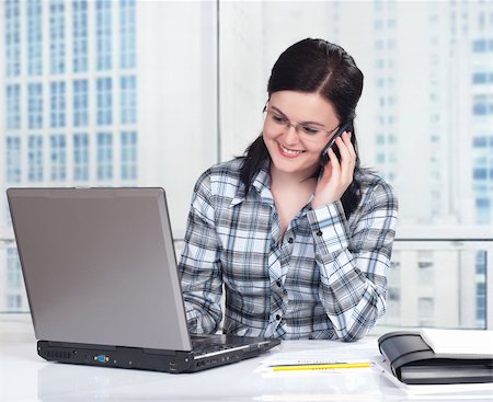 simsearch:400-05287143,k - Portrait of a pretty young woman with phone in front of a laptop computer Stock Photo - Budget Royalty-Free & Subscription, Code: 400-04847967