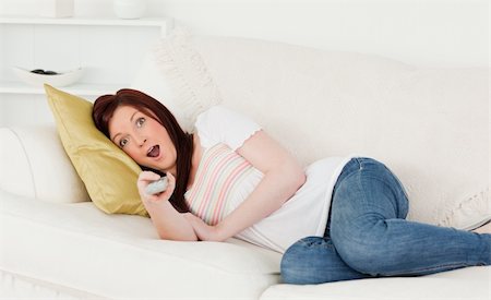 Attractive red-haired woman watching tv while lying on a sofa in the living room Stock Photo - Budget Royalty-Free & Subscription, Code: 400-04878621