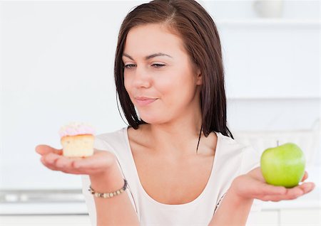 simsearch:400-05106591,k - Charming woman with an apple and a piece of cake looking at the cake Stock Photo - Budget Royalty-Free & Subscription, Code: 400-04884057