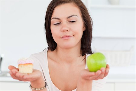 simsearch:400-05106591,k - Close up of a cute brunette with an apple and a piece of cake looking at the apple Stock Photo - Budget Royalty-Free & Subscription, Code: 400-04884061