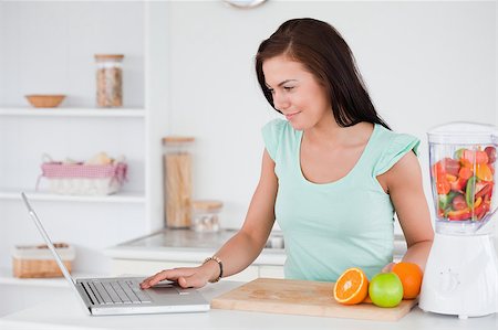 Woman with a laptop and fruits in a blender in her kitchen Stock Photo - Budget Royalty-Free & Subscription, Code: 400-04884114