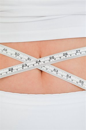 simsearch:400-07219376,k - Young woman measuring her belly with a tape measure while standing in her bedroom Stock Photo - Budget Royalty-Free & Subscription, Code: 400-04882158