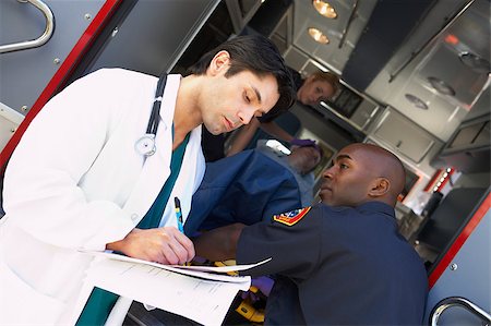 simsearch:400-05343071,k - Hospital doctor taking notes as paramedics arrive with patient Stock Photo - Budget Royalty-Free & Subscription, Code: 400-04890165