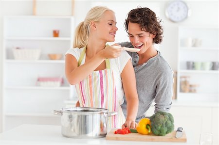 simsearch:400-05740111,k - Woman making her fiance tasting her meal while wearing an apron Stock Photo - Budget Royalty-Free & Subscription, Code: 400-04904435