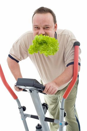 fat man exercising - Power slimming concept with overweight man on exercise machine eating fresh green salad - isolated Stock Photo - Budget Royalty-Free & Subscription, Code: 400-04916147