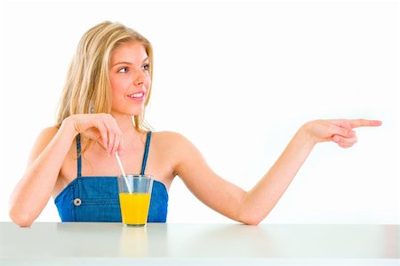 simsearch:400-05888428,k - Cheerful teen girl with orange juice pointing in corner Stock Photo - Budget Royalty-Free & Subscription, Code: 400-04917137
